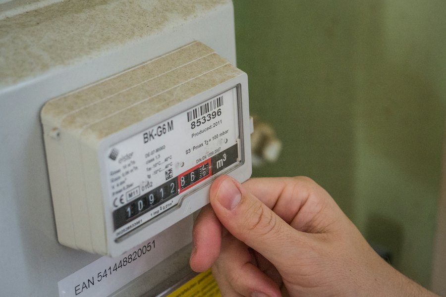 Hånd ved en energimåler, der måler strømforbruget